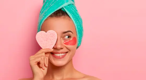 امرأة تستخدم منتجات عناية مستهدفة تشمل لصقة تحت العين وإسفنجة وجه ضمن روتين موجّه