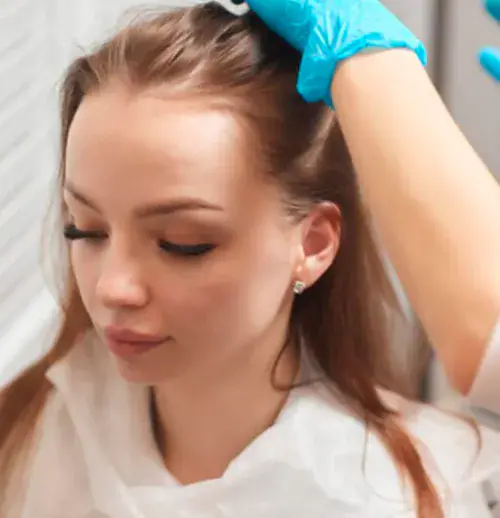 Medical professional in blue gloves examining a woman's scalp during a PDRN treatment consultation in Dubai