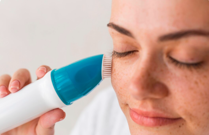 Professional pigmentation treatment with a handheld skincare device being applied to a patient's cheek in a clinical setting