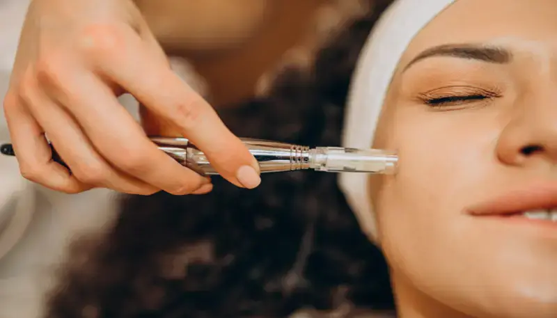 Relaxed woman receiving professional RF microneedling facial treatment for collagen remodeling and skin tightening at Dr. Elham Keikha clinic in Dubai