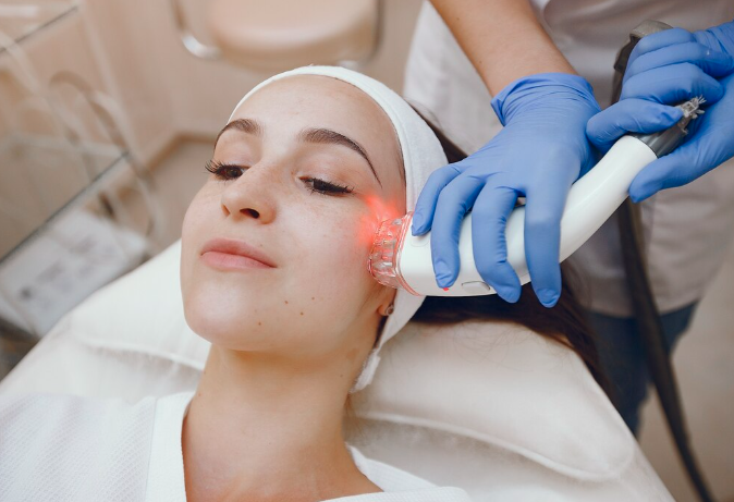 Advanced red light laser therapy for melasma being performed on a patient's cheek by a practitioner in blue gloves at a Dubai clinic